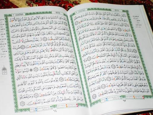An open Mushaf with colour-coded Tajweed rules
